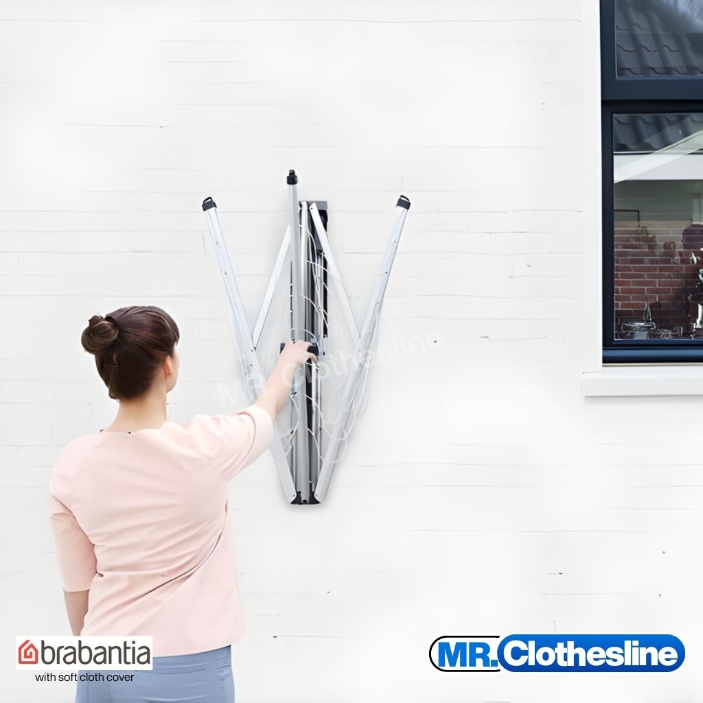 A woman opening up the wall fix clothesline with one hand.