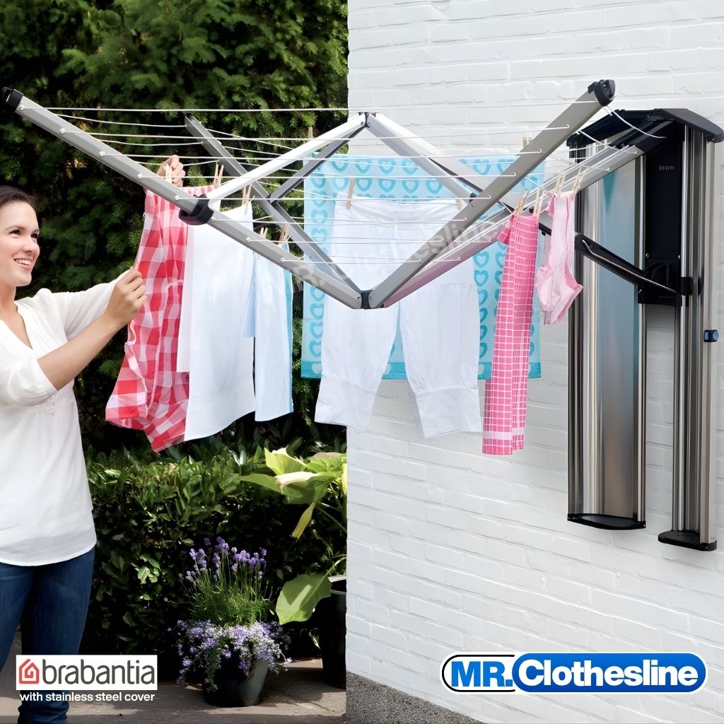 Brabantia wall fix clothesline being used outside by a woman smiling.  Stainless steel cover is open showing it as permanent fixture.