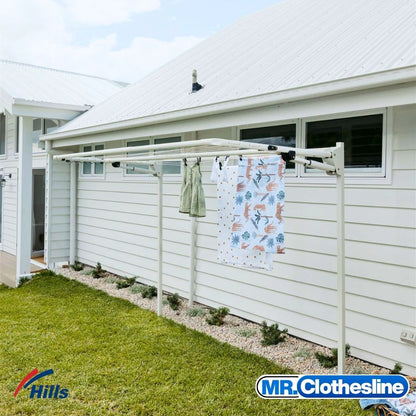 Hills Double Fold Down Clothesline installed outside using ground mount kit inserted into soil beside home exterior.