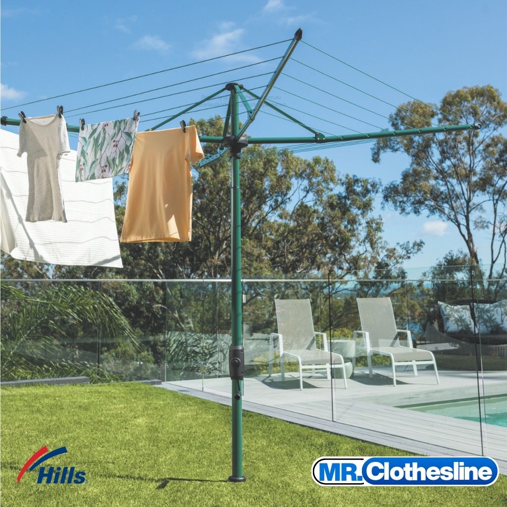 Hills Folding Rotary 6-Line Clothesline in Cottage Green installed on lawn beside pool with washing hanging on it.