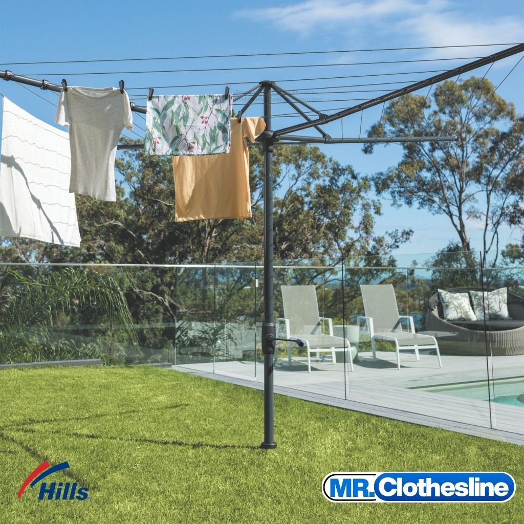 Hills Folding Rotary 8-Line Clothesline in Monument colour installed in backyard lawn beside pool.