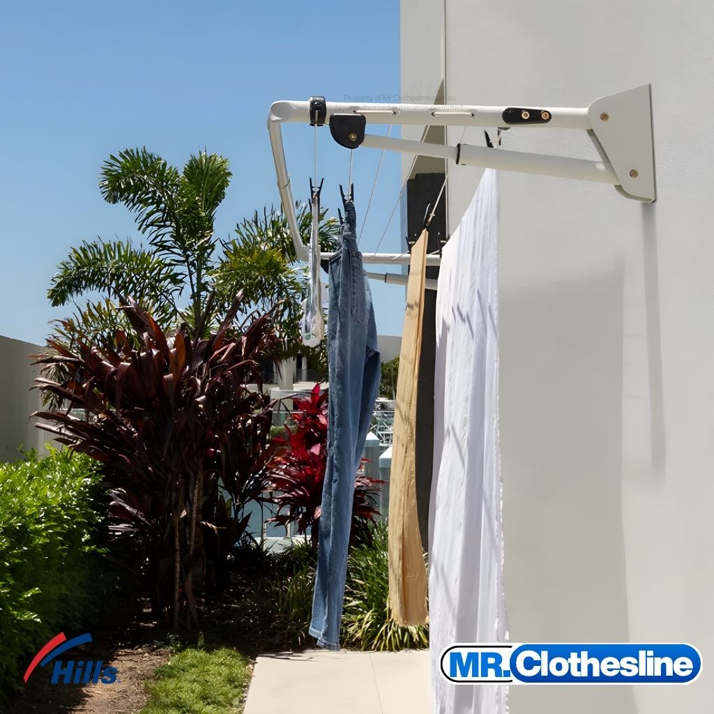 Hills Long Fold Down Clothesline installed outside in white with washing hanging on lines, wall-mounted to home exterior, Surfmist colour.