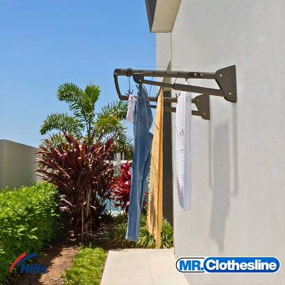 Hills Mini Fold Down Clothesline installed outside in Monument colour with washing hanging on lines, mounted to exterior wall.