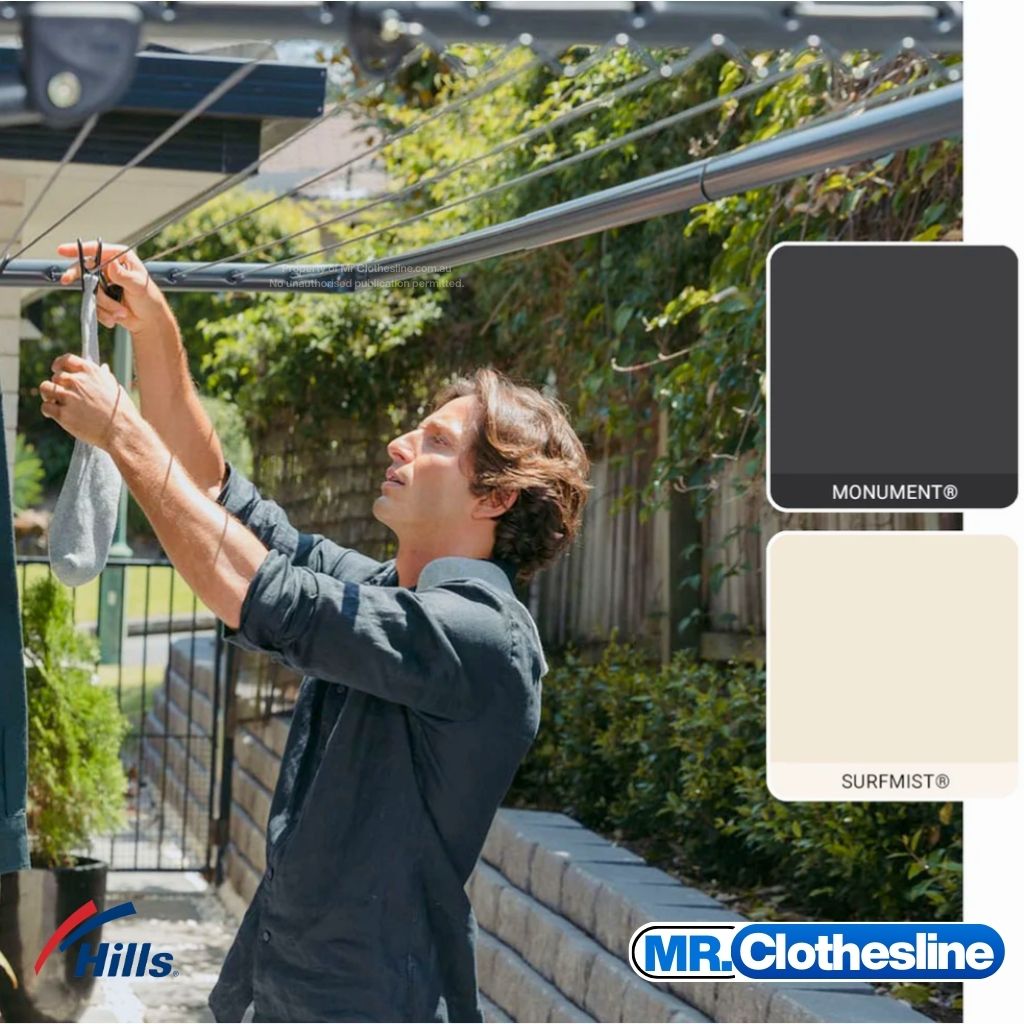 Man hanging washing on Hills Single Fold Down Clothesline outdoors, with Monument and Surfmist colour swatches shown.